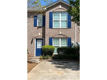Charming brick townhome featuring blue shutters, a well-maintained lawn and inviting curb appeal at 212 Meadowlark Place, Austell, GA 30168