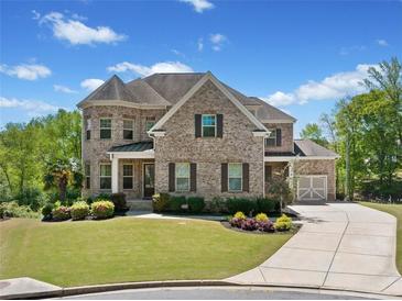 Beautiful two-story brick home with a well-manicured lawn and attached garage on a sunny day at 6090 Pennant Ln, Suwanee, GA 30024