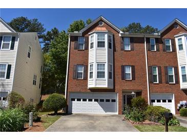 Two-story red brick townhome with a two-car garage and well-manicured landscaping at 5229 Pinnacle Pointe Ct, Norcross, GA 30071