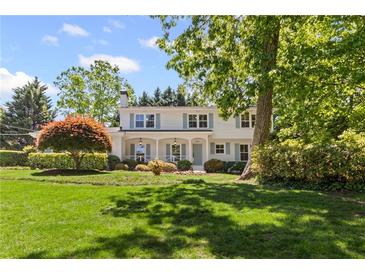 Charming two-story traditional home with manicured lawn, mature trees, and light blue shutters at 1047 Winding Branch Ct, Atlanta, GA 30338