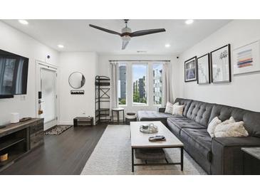 Bright living room features dark wood floors, ceiling fan, and large couch with lots of sunlight at 1050 Stacks Ave # 1507, Atlanta, GA 30315