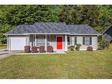 Charming home with a well-manicured lawn and a bright red front door adding a pop of color at 6895 Brown S Dr, Fairburn, GA 30213