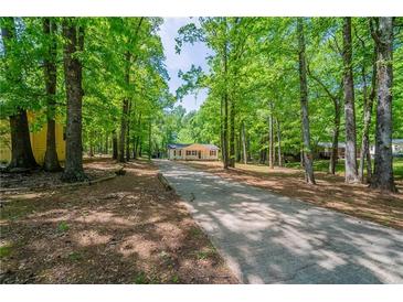 Ranch home with a charming front porch, nestled among mature trees and a long drive at 210 Meadowbrook Dr, Mcdonough, GA 30253