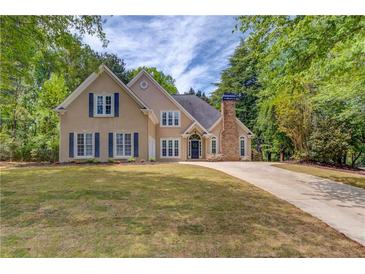 Charming two-story home featuring a manicured lawn, neutral siding, blue shutters, and a stone chimney at 12340 Preserve Ln, Alpharetta, GA 30005