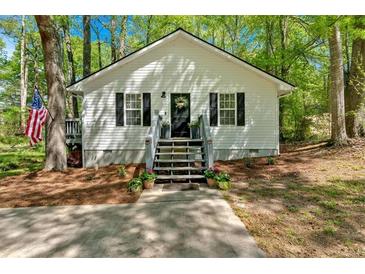 Charming exterior with an American flag, flower pots, a black door, and black shutters at 113 Fowler Dr, Bowdon, GA 30108
