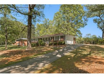 Charming brick home featuring a long driveway and mature trees on a sunny day at 1788 Hammond Woods Sw Cir, Marietta, GA 30008