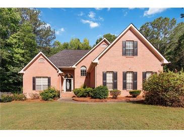Charming brick home featuring a well-manicured lawn and inviting curb appeal with classic shutters at 219 Garden W Walk, Hampton, GA 30228