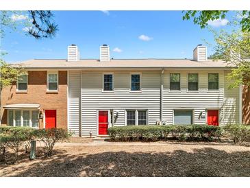 Charming townhome featuring a brick and vinyl exterior, manicured landscaping, and inviting red front doors at 223 Chads Ford Way, Roswell, GA 30076