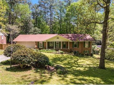 Charming brick home featuring lush landscaping, green shutters, and an attached two-car garage at 2927 Ponderosa Cir, Decatur, GA 30033