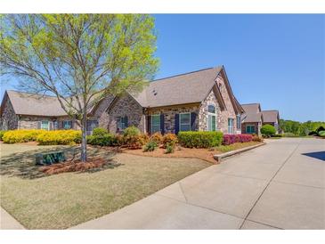 Charming brick home featuring a well-manicured lawn, mature tree, colorful shrubs and an inviting driveway at 4321 Lanier Ridge Walk # 1704, Cumming, GA 30041