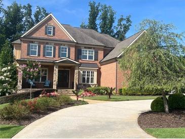 Stunning brick home featuring a manicured lawn, a circular driveway, and mature landscaping at 2331 Kinsale Nw Pt, Kennesaw, GA 30152