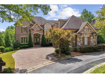 Beautiful brick and stone two-story home with a well-manicured lawn and circular brick driveway at 5422 Heyward Square Pl, Marietta, GA 30068