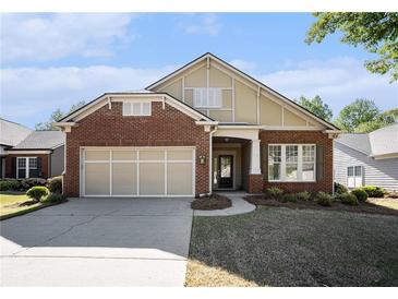 Charming brick home featuring a two-car garage, manicured lawn, and inviting entrance at 4930 Kings Common Way, Cumming, GA 30040