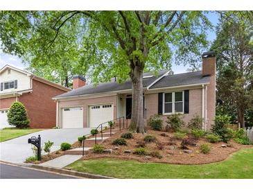 Charming brick home featuring a two-car garage, mature trees, and a well-manicured front yard at 1205 Club Walk Ne Dr, Brookhaven, GA 30319