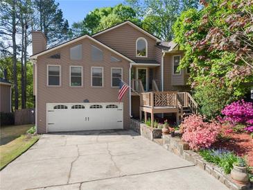 Charming two-story home features a two-car garage, inviting front porch, and beautifully landscaped front yard at 440 Hunt River Way, Suwanee, GA 30024