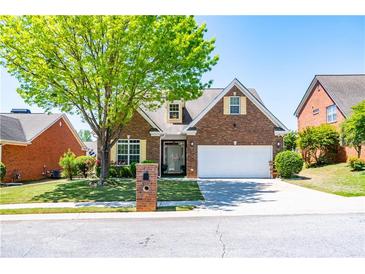 Charming brick home featuring a well-manicured lawn, mature tree, and two-car garage at 8531 Spivey Village Trl, Jonesboro, GA 30236