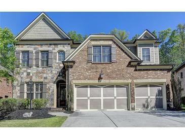 Charming brick and stone home with a three-car garage and manicured front yard at 3330 Camellia Ln, Suwanee, GA 30024
