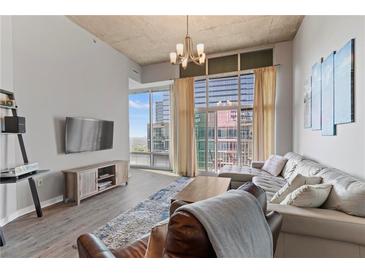 Bright living room featuring hardwood floors, modern decor, and expansive windows with city views at 943 Peachtree Ne St # 2002, Atlanta, GA 30309