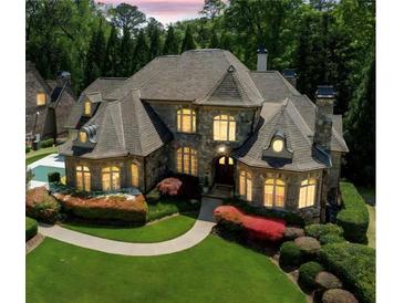 Stunning stone home boasts a lush lawn, manicured landscaping, and elegant architectural details at 841 Camden Park Ne Ct, Atlanta, GA 30342