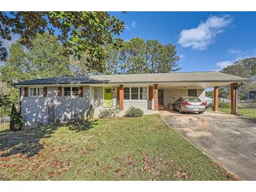 Charming exterior featuring a light grey brick facade, lime green front door, and covered carport at 2376 Falls River Dr, Lithia Springs, GA 30122