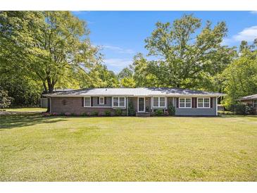 Charming single-story home with brick and gray siding, complimented by a well-manicured green lawn at 4715 Howard Dr, Powder Springs, GA 30127