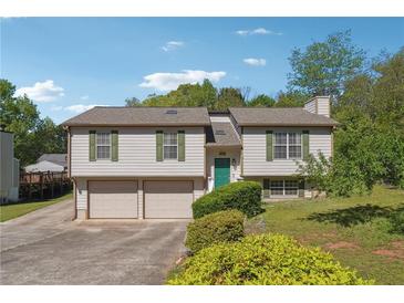 Split-level home featuring attached garage, manicured lawn, and welcoming, bright green front door at 2816 Pine Meadow Dr, Marietta, GA 30066