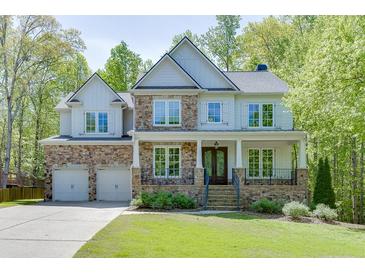 Beautiful two-story home with stone and siding exterior, well-manicured lawn, and a welcoming front porch at 7035 W Mountain Xing, Cumming, GA 30041