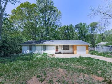Modest one-story home featuring vinyl siding, an attached garage, and mature trees in the front yard at 1527 Keeter Rd, Canton, GA 30114