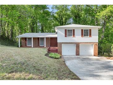 Split-level home showcasing brick and white siding, complemented by an expansive driveway and lush surroundings at 46 Hawkins Store Nw Rd, Kennesaw, GA 30144