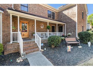 Charming brick home featuring a welcoming front porch with decorative details and landscaped garden at 5000 Bainbridge Sw Ct, Lilburn, GA 30047