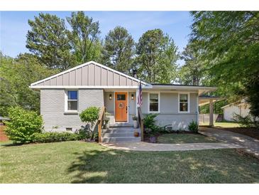 Charming single-story home with a well-manicured lawn and an inviting orange front door at 1079 Pinedale Se Dr, Smyrna, GA 30080