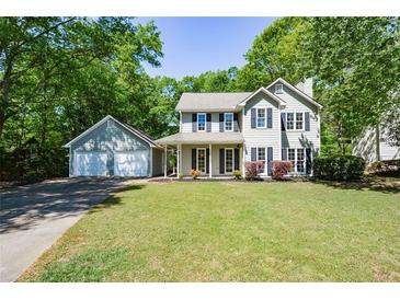 Charming two-story home with a lush green lawn and a detached two-car garage, surrounded by mature trees at 605 Sutton Sw Way, Marietta, GA 30064