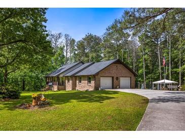 Charming single-story brick home featuring an attached two-car garage and a sprawling front lawn with mature trees at 3400 Bonds Lake Nw Rd, Conyers, GA 30012