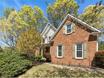 Charming brick home featuring green shutters, mature landscaping, and a well-maintained lawn at 6105 Ivey Hill Dr, Cumming, GA 30040