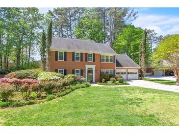 Charming brick home featuring a manicured lawn, black shutters, and an attached two car garage at 2830 Scottish Mill Way, Marietta, GA 30068