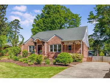 Charming brick home featuring a well-manicured lawn, mature trees, and welcoming front porch at 1256 Spring Valley Ne Ln, Atlanta, GA 30306