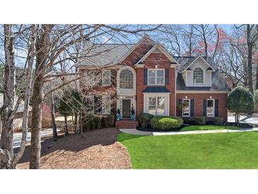 Beautiful two-story red brick home with arched window and manicured lawn at 720 Lakeglen Dr, Suwanee, GA 30024