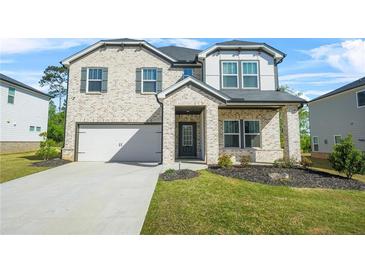 Charming two-story home featuring a brick facade, well-manicured lawn, and an attached two-car garage at 802 Milo Bay St, Loganville, GA 30052