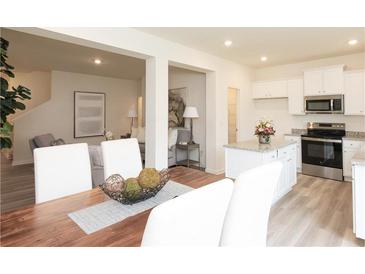 Bright dining area with wood table, white chairs, and an open view of the modern kitchen and comfortable living room at 2680 Ne Almand Ne Ln, Conyers, GA 30013