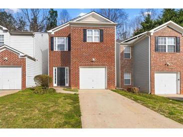 Charming townhouse featuring a brick facade, single car garage, and well-maintained front lawn at 2825 Windsor Forrest Ct, Atlanta, GA 30349