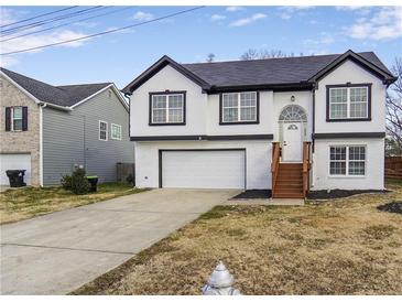 Charming two-story home featuring a white exterior, contrasting black trim, an attached garage, and a well-maintained front yard at 3094 Jonesboro St, Ellenwood, GA 30294