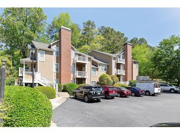 A tan building with a brick chimney and multiple balconies, surrounded by green trees and a parking lot in front at 5566 River Heights Se Xing, Marietta, GA 30067