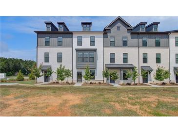 Modern townhomes with white brick, gray accents, dormer windows, and professionally landscaped front yards at 529 Rubato Knl, Mcdonough, GA 30253