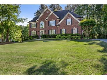 Beautiful two-story brick home with manicured lawn and mature trees providing shade and curb appeal at 7115 Doncaster Ct, Cumming, GA 30040