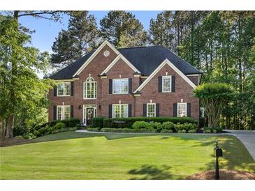 Traditional brick home with well-manicured lawn, lush landscaping, and a welcoming front entrance at 7115 Doncaster Ct, Cumming, GA 30040