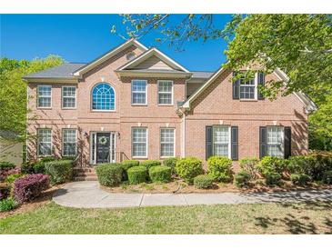 Charming brick home featuring a manicured front yard, mature landscaping, and inviting entrance at 1010 Forest Creek Dr, Canton, GA 30115
