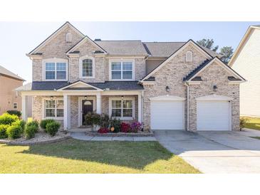 Charming two-story brick home featuring a manicured lawn, flower beds, and a two-car garage at 3448 Clear Stream Ne Run, Auburn, GA 30011