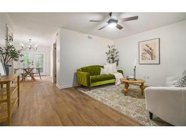Inviting living room featuring a stylish green sofa, wood floors, and natural light at 2294 Salt Springs Pl, Austell, GA 30168