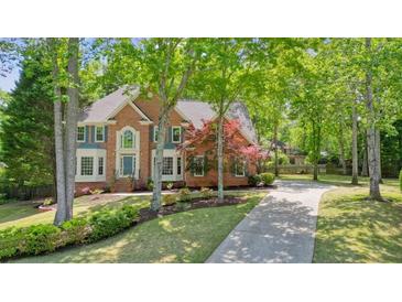 Beautiful brick home featuring a well-manicured lawn, mature trees, and a long driveway at 120 Stanmore Ct, Roswell, GA 30075