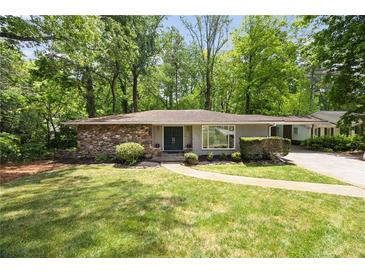 Charming single-story home with stone accents, a well-manicured lawn, and mature trees creating a private setting at 239 Devonwood Dr, Atlanta, GA 30328